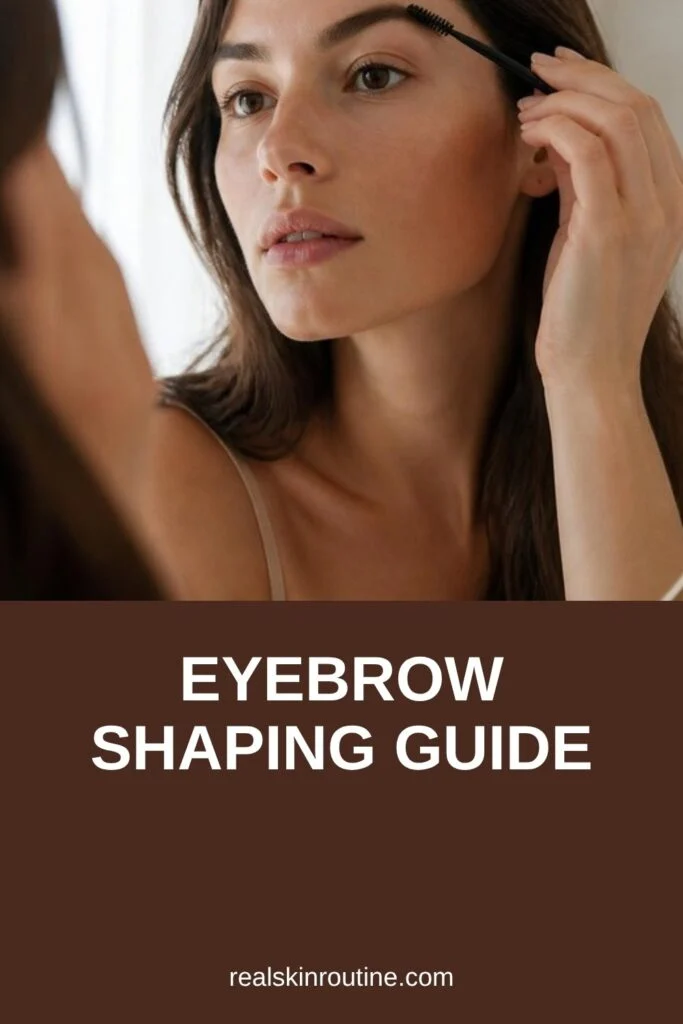 Woman brushing her eyebrows up with a spoolie in a mirror, pin for eyebrow shaping